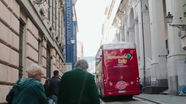 Menschen gehen in einer Stadt durch eine Fußgängerzone. Ein Touristenbus fährt vorbei — Stockvideo