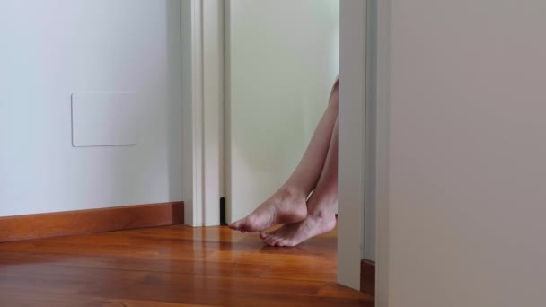 ドアの後ろに座っている若い女性の足. — ストック動画
