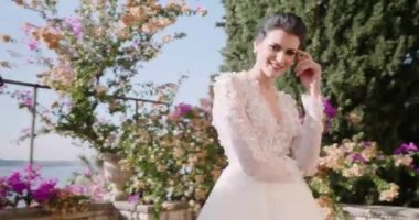 Beyaz gelinlikli genç kadın egzotik adadaki balkonda yürüyor. Kapat