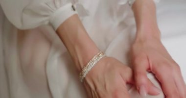 Kadın elleri ile beyaz gelinlik trenini ayarlıyor.