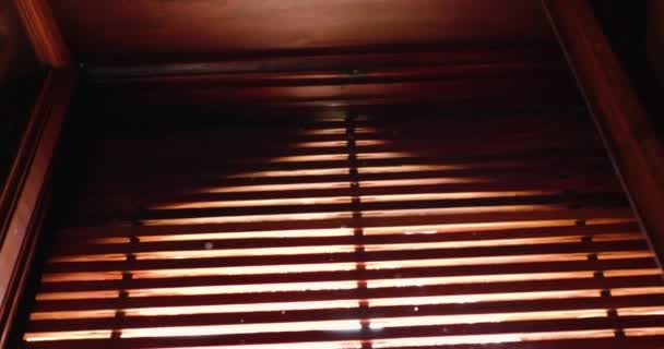 Сонячне світло пробивається крізь віконні жалюзі освітлення кімнати — стокове відео