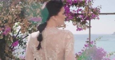 Beyaz gelinlikli genç kadın egzotik adanın balkonunda yürüyor. Kapat