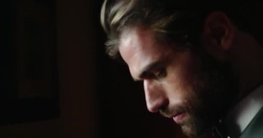 Genç sakallı adam pencerede duruyor ve düğüne hazırlanıyor.