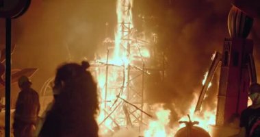 İnsanlar İspanya 'daki Las Fallas festivalinde yanan oyuncak bebeklerin dev figürlerini izliyor.