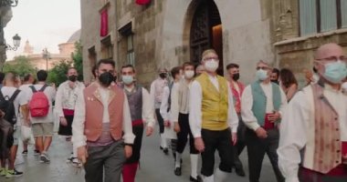 Kostüm giymiş insanlar yolda yürürken alkışlıyorlar.