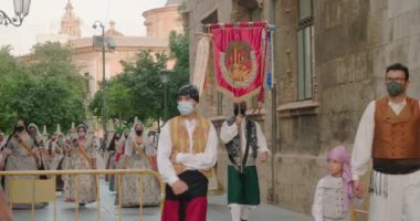 Kostüm giymiş insanlar yolda yürürken alkışlıyorlar.