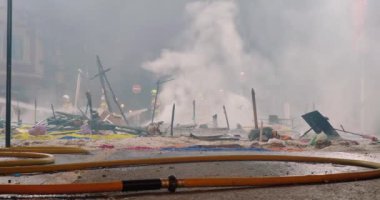Yanan heykelleri söndürdükten sonra yangın hortumu. İnsanlar kutlamalardan sonra dağılır.