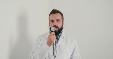 Steteskop taklit eden mikrofonlu doktor ofiste şarkı söyleyip dans ediyor. Genç terapist, öğle tatilinde iş yerinde eğleniyor.