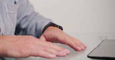 Bilinmeyen adam nöbetteki zamanı kontrol ediyor son teslim tarihinden önce laptopta rapor bitirmeye çalışıyor. Çalışan ofiste çalışıyor. Bej duvarlara karşı masasında oturuyor.