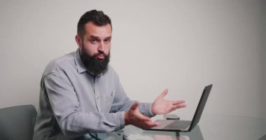 Yetenekli koç, kromakey yeşil dizüstü bilgisayarı kameraya dönüştüren örnekler gösteren web sitesi yaratmayı açıklıyor. Sakallı adam ofiste masa başında oturuyor.