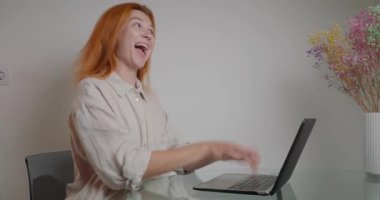 Duygusal kadın işini çabuk bitirmek için bilgisayarın klavyesine basıyor. Kızıl saçlı bayan ofisindeki cam masada oturuyor, görevlerini tamamlıyor, vazodaki çiçeklerin yanında klavyeye yazı yazıyor. 