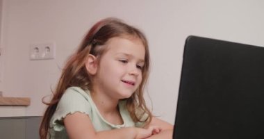 Çalışkan liseli kız, bilgisayar aracılığıyla video konferansında öğretmeniyle iletişim kurarak masa başında oturuyor. Küçük kız evde internetten eğitim görüyor.