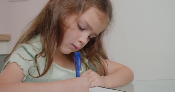 Junior Skolepige Udfører Opgave Skriftligt Med Pen Øvelsesbog Lille Pige – Stock-video