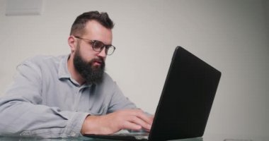 Deneyimli programcı dizüstü bilgisayarda kod yazar. Ofiste oturmaktan yorulduğunu hisseder. Sakallı adam gözleri ovalamak için gözlüğünü çıkarır ve çalışmaya devam eder.