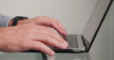 Adam, dizüstü bilgisayarı izleme ve kapatma saatine bakarak projeyi kontrol ediyor. Son teslim tarihinde acele eden işçiler cam masadan elektronik cihazı alıp yakın plan çekime alıyorlar.