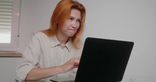 彼女は同僚と冗談を中断し 笑いノートパソコンで動作します 長い緩い生姜の髪を持つ陽気な女性はオフィスルームで職場で楽しみを持っています — ストック動画