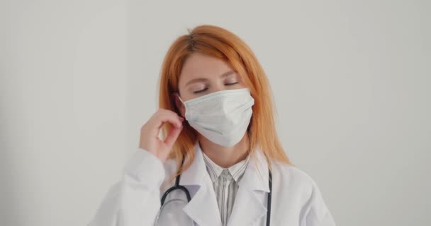 Médica Ruiva Tira Máscara Médica Olha Tristemente Para Câmera Senhora — Vídeo de Stock