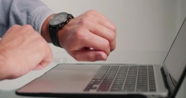 Adam, dizüstü bilgisayarı izleme ve kapatma saatine bakarak projeyi kontrol ediyor. Son teslim tarihinde acele eden işçiler cam masadan elektronik cihazı alıp yakın plan çekime alıyorlar.