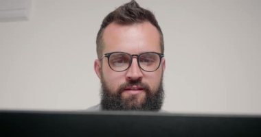 Gözlüklü bir çalışan yeni projeyi konuşmak için telefonda müdürle görüşüyor. Sakallı adam masa başında oturup ofiste bilgisayarla yakından ilgileniyor.