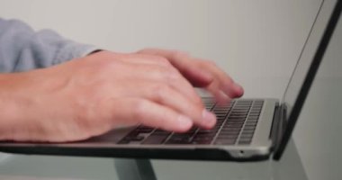 Klavyede serbest çalışan tipler yeni başlatılan proje hakkında makale yazıyorlar. Cam masanın üzerinde duran cihazdaki düğmelere basan adamın elleri.