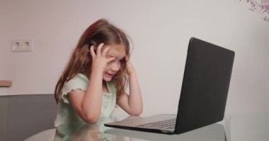 Dizüstü bilgisayarında baş parmak hareketi gösteren neşeli kız tipleri. Küçük bir okul öğrencisi evdeki modern aletleri kullanarak öğreneceği için heyecanlanıyor.