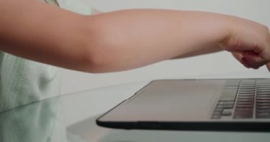 Küçük kızlar masadaki dizüstü bilgisayarın tuşlarına basarak kelimeler yazıyorlar. Okul çocuğu evdeki modern aygıtı kullanarak çevrimiçi derse hazırlanıyor