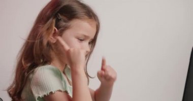 Masada oturan küçük kızın fikri vardı ve modern cihazın klavyesindeki tuşlara basıyordu. Meraklı liseli kız dizüstü bilgisayarda yazmayı evde öğreniyor.