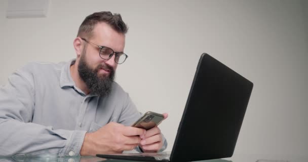 Bearded Man Browses Social Networks Smartphone Instead Work Laptop Employee — Stock Video