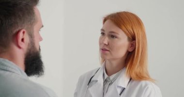 Kadın doktor, klinikteki erkek hastaya danışmanlık yapıyor. Bayan pratisyen doktor randevudaki olgun sakallı adama tedavi yöntemini açıklıyor.