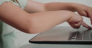 Küçük kızlar masadaki dizüstü bilgisayarın tuşlarına basarak kelimeler yazıyorlar. Okul çocuğu evdeki modern aygıtı kullanarak çevrimiçi derse hazırlanıyor
