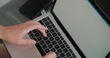 Kadın yeni web sitesi için modern dizüstü bilgisayarda içerik yazıyor. Fotokopi yazarının elleri telefonun yakınındaki masada cihazın klavyesindeki tuşlara basar