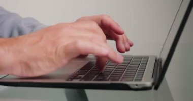 Klavyede serbest çalışan tipler yeni başlatılan proje hakkında makale yazıyorlar. Cam masanın üzerinde duran cihazdaki düğmelere basan adamın elleri.
