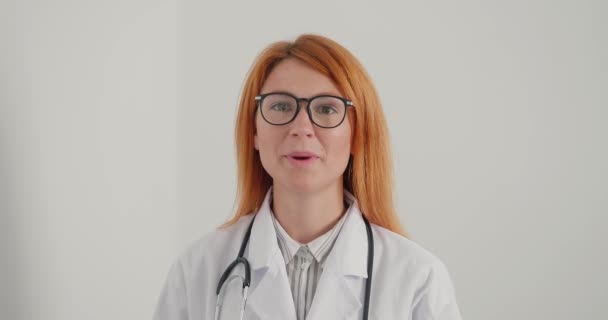 Женщина Врач Очках Рыжих Волосах Улыбается Дает Советы Глядя Камеру — стоковое видео