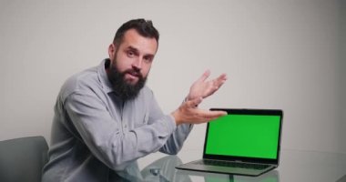 Profesyonel koç, dizüstü bilgisayardaki kromakey yeşil ekranda örnekler gösteren kod yazmaktan bahsediyor. Sakallı adam ofiste online video kursu yönetiyor.