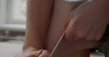 Elastic felt hat body takes form of mold standing at table in workshop. Woman pulls hat stretching material. Process of making headwear closeup