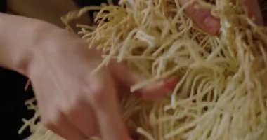 Hands of woman touch material for making wicker hats on wooden shelf. Professional milliner creates handmade headwear for sale closeup