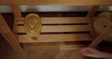 Milliner puts wooden molds for hats shape in order on shelf in workshop. Woman arranges equipment after finishing work with headwear closeup