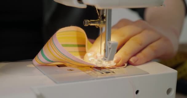 Woman Uses Sewing Machine Sew Wide Colorful Hat Ribbon Sitting — ストック動画