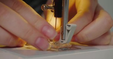 Woman puts pink thread into needle hole of sewing machine on grey background. Milliner prepares equipment for work in workshop extreme closeup