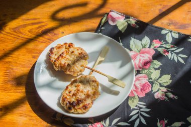 A bag of glutinous rice and two grilled pork are placed in a plate on a table by the window.