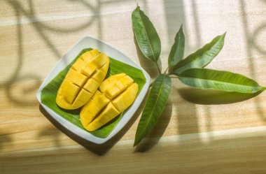 Olgun mangolar tabağa konur ve masaya yapraklar konur..