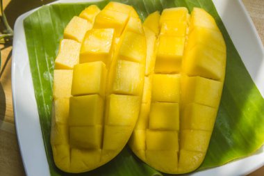 Olgun mangolar masanın üzerindeki bir tabağa konur. Masanın üzerindeki bir tabağa yerleştirilir..