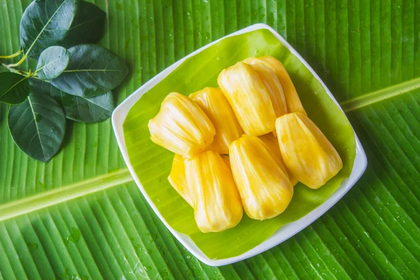 Olgun meyvelerin birçok özelliği vardır. Muz yapraklarıyla kaplı beyaz bir tabağa koy..