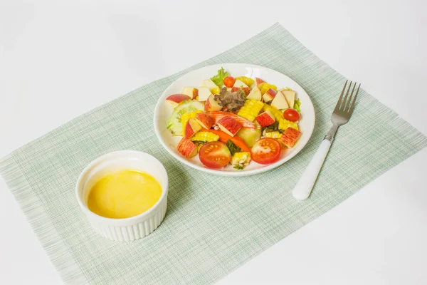 白を基調としたサラダドレッシングのボウルに白いプレートにカニの棒と果物や野菜のサラダを混合 — ストック写真