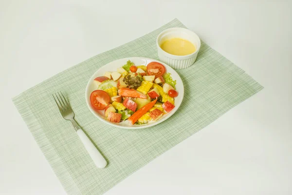 白を基調としたサラダドレッシングのボウルに白いプレートにカニの棒と果物や野菜のサラダを混合 — ストック写真