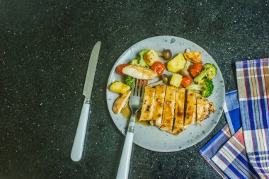 Izgara tavuk göğsü, biftek, biftek, patates, vişneli domates, siyah tabakta brokoli..