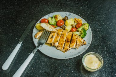 Izgara tavuk göğsü, biftek, biftek, patates, vişneli domates, siyah tabakta brokoli..