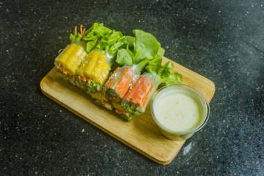 Ahşap doğrama tahtasına karışık salata rulosu ve soslu sağlıklı yiyecek konsepti.