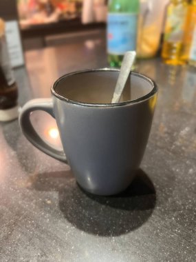 Mutfaktaki koyu siyah mermer bir masada, gri seramik bir kahve fincanında dikey yakın plan.