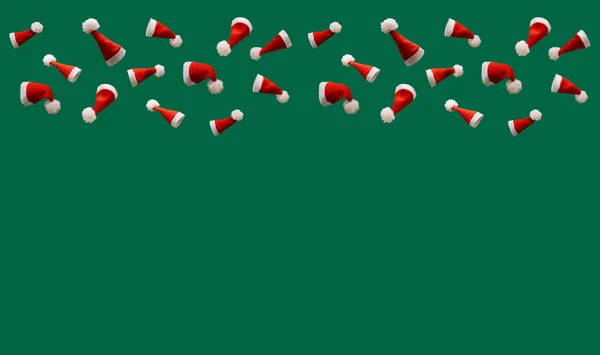 Yeşil arka planda kırmızı Noel şapkaları, metin için boş alanı olan yaratıcı Noel konsepti